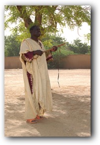 Griot jouant du Xalam sous un acacia